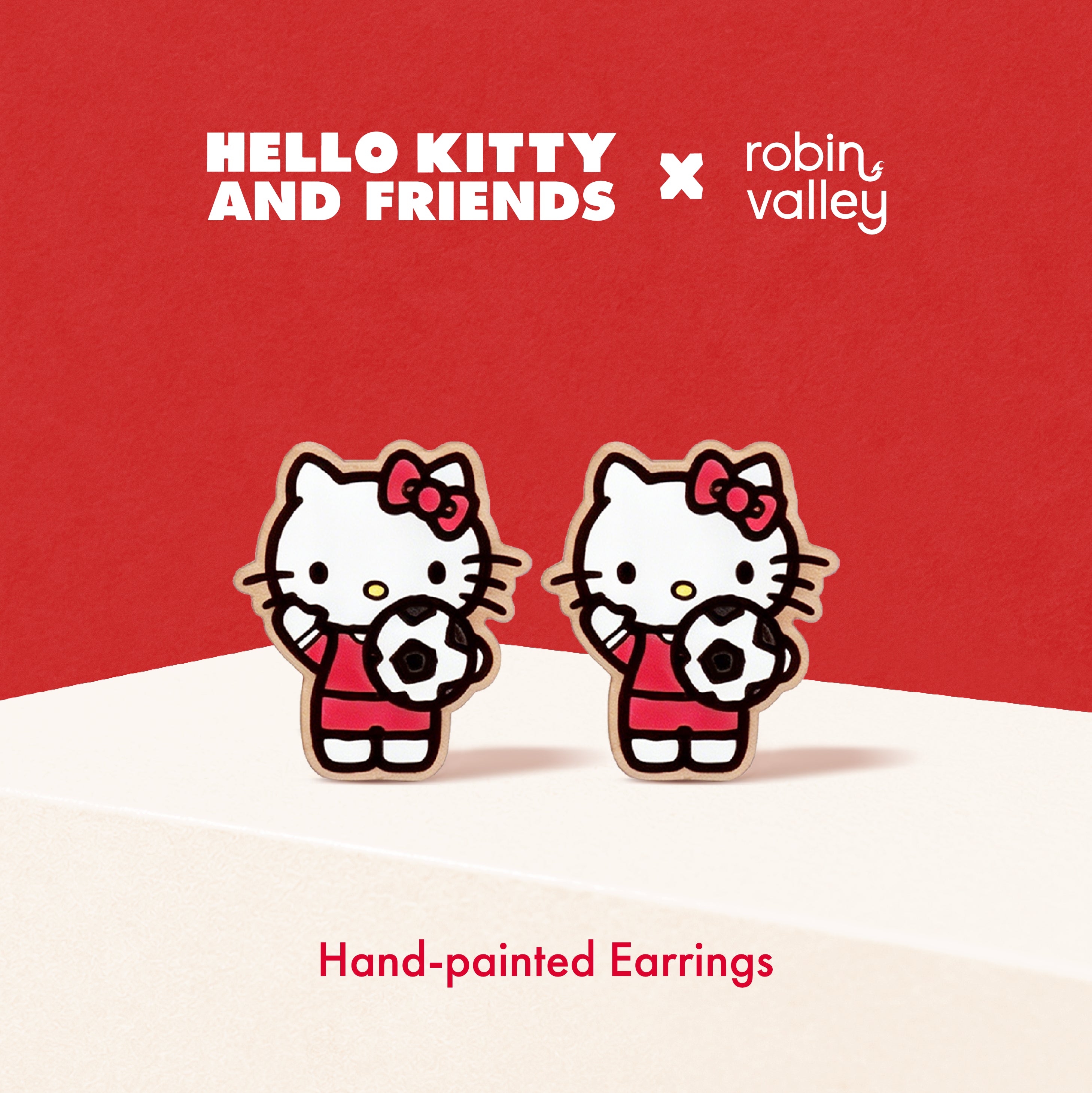 Hand-painted earrings of Hello Kitty holding soccer balls on a red background with 'Hello Kitty and Friends' and 'Robin Valley' branding.